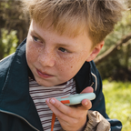 Boy using Waffle Go screen-free phone to make a call outdoors, ages 5-12