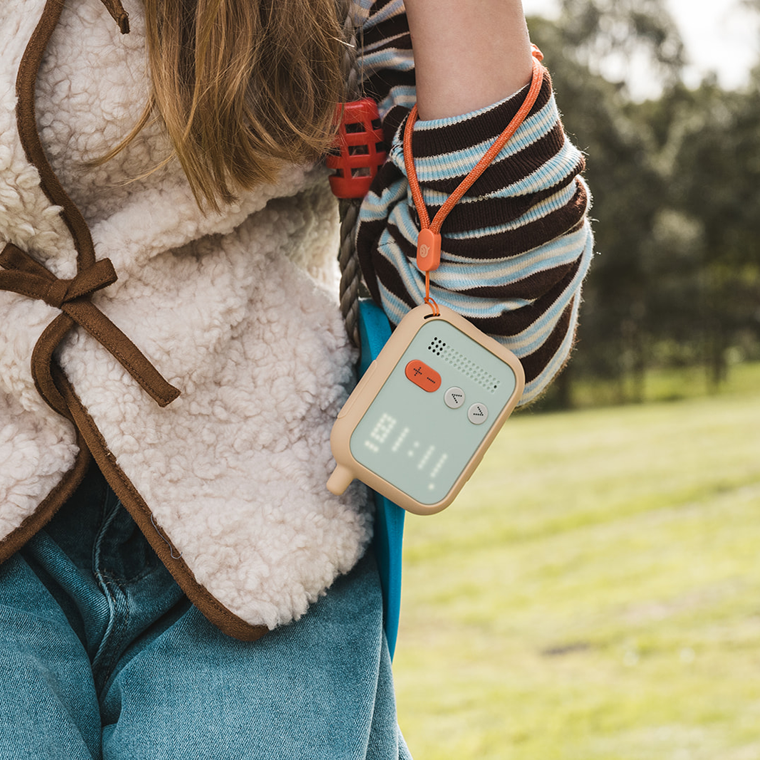Girl holding Waffle Go screen-free kids phone on lanyard outdoors