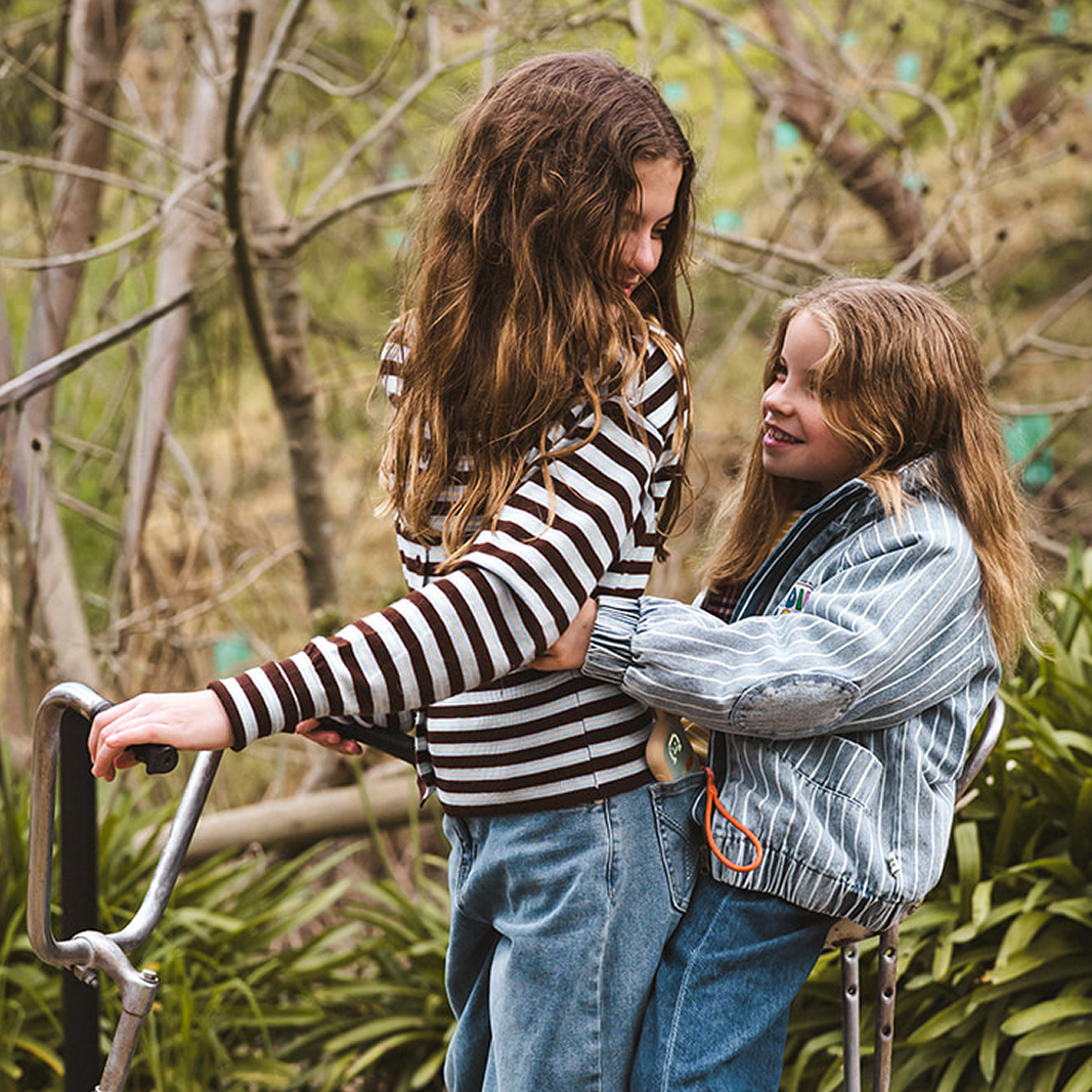 Two girls playing outdoors with Waffle Go screen-free phone with lanyard around wrist