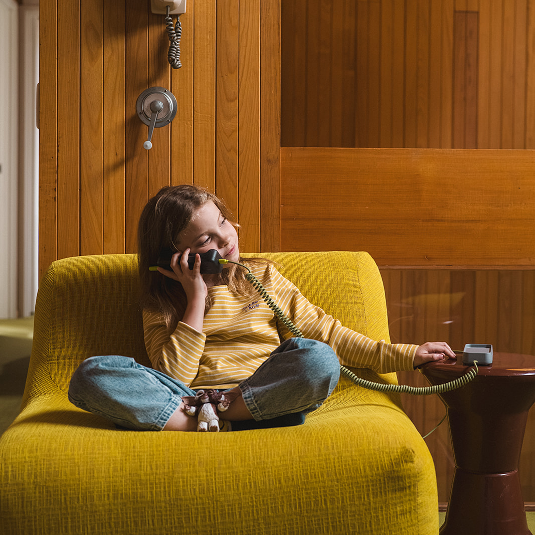 Girl relaxing on sofa talking on Waffle Home screen-free WiFi phone for kids